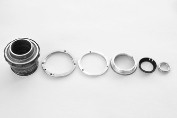 Details of the old manual lens, free space. A disassembled lens lined up in a row on a white...