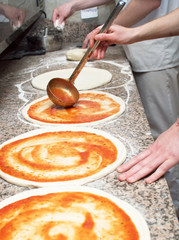 Cook in the kitchen putting the ingredients on the pizza. Pizza concept. Production and delivery of food.