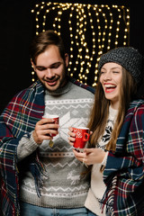 Couple drinking tea while woman joking on her partners account