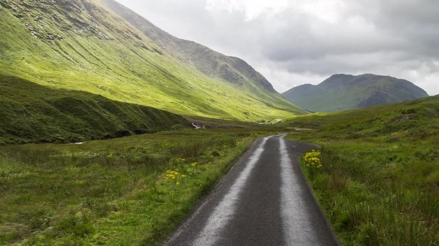 POV shot from a camera attached to the front of a vehicle driving through beautiful empty roads in the scottish highlands