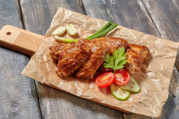 Crispy baked chicken wings on wooden board