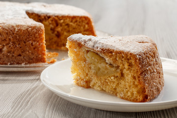 Sliced homemade apple pie on glass plate and piece of pie on white ceramic plate