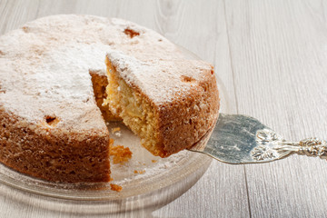 Sliced homemade apple pie on glass plate and piece of pie on silver cake lifter