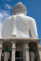 Fototapeta premium Rear view of Big Buddha stone monument against blue cloudy sky background