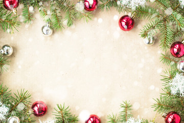 Fototapeta na wymiar Festive christmas border with red balls on fir branches and snowflakes with snow on rustic beige background
