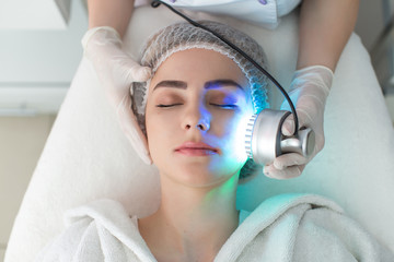 Ultrasonic massager. Light skin treatment, the woman in the beauty salon