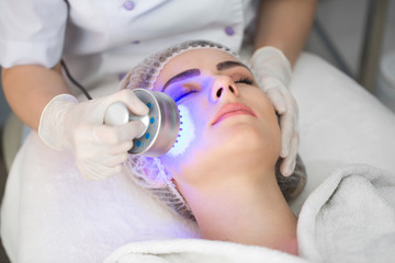 Obraz na płótnie Canvas Ultrasonic massager. Light skin treatment, the woman in the beauty salon