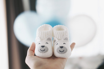 baby shoes in hand with balloon background