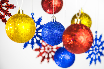 Beautiful Christmas and New Year colorful background. Close up of red, blue, golden shining ornaments hanging on glossy silver ropes isolated on white. Horizontal color phtography.