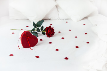Valentines day surprise at morning on the white bed for her. Red heart background with rose with...