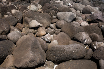 Large black stones on the shore of the Indian ocean. Mauritius.