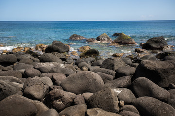 Fototapeta na wymiar Large black stones on the shore of the Indian ocean. Mauritius.