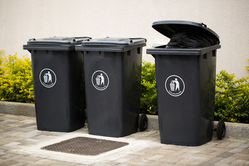Black indoor waste containers for recycling and garbage. A lot of closed and recycle receptacles trash bin outside - obrazy, fototapety, plakaty
