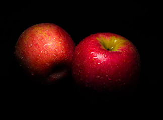 Water droplet on glossy surface of red apple on black background