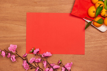 Top view accessories Chinese new year festival decorations.orange,leaf,wood basket,red packet,plum blossom on red background.