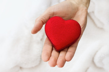 Heart symbol in men hand. Giving a red heard. Copy space for text. Background for Valentine's Day. Heart as a gift.
