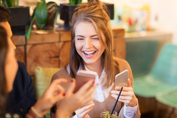woman with smartphone and friends at restaurant