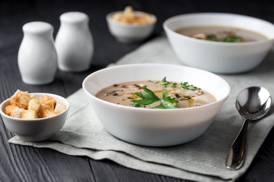 Mushroom cream soup with herbs and spices over rustic wooden background