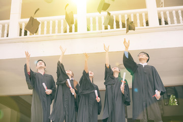 Graduating Students holding their diploma and throwing Caps in the Air