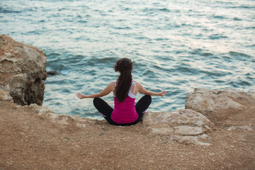 Fototapeta na wymiar Caucasian woman practicing yoga at seashore of ocean