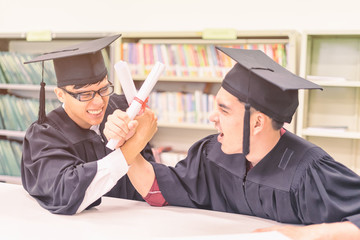 Obraz premium graduate students holding their diploma and arm wrestle