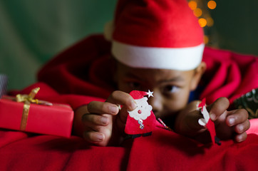 Little Asian Boy Hold Santa Icon on the Bed in Christmas 's Day.