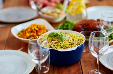 pasta with basil in bowl and other food on table