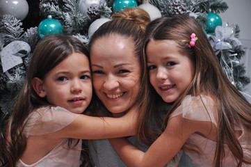 Two little girls hugging their mom. Smiling daughters hugging mom for Christmas