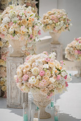Beautiful bouquet of roses in a vase on a background of a wedding arch. Beautiful set up for the wedding ceremony.
