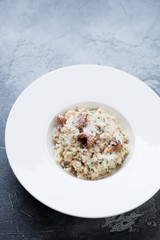 Plate of risotto with chanterelles over grey stone surface, vertical shot with copyspace