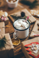 Cup of hot chocolate with marshmallows on wooden table with Christmas gifts 