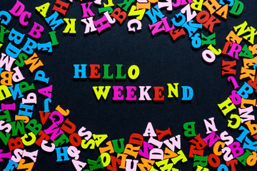 Naklejka premium concept design - the word HELLO WEEKEND from multi-colored wooden letters on a black background, creative idea