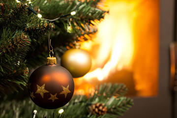 decorations on christmas tree and fire burning in fireplace in the background