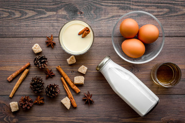 Make eggnog classic recipe. Eggs, milk, cinnamon, whiskey on dark wooden background top view