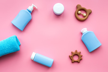 Natural hypoallergenic children's cosmetics. Bottles, towel and toys on pink background top view copyspace