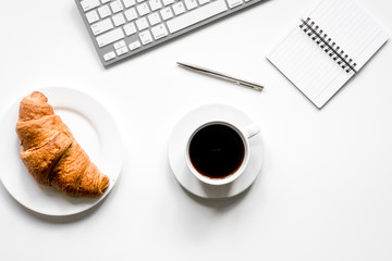 Business breakfast in office with notebook, coffee and croissant