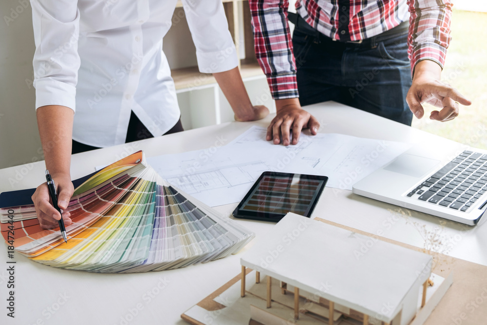 Poster Two interior design or graphic designer at work on project of architecture drawing with work tools and color swatches, colour chart, color samples for selection, renovation and technology concept