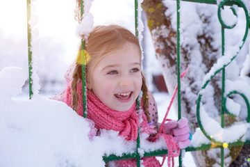 girl in the winter in the sun. bright winter photo of a girl near a fence with snow