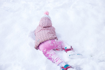 the child is playing in the snow. girl sports and has fun in winter