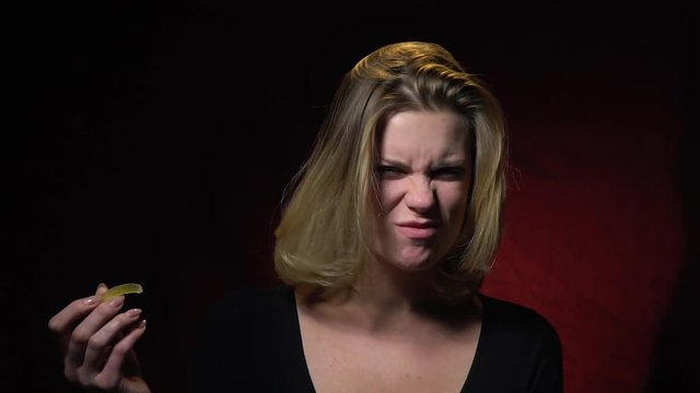 Blonde in a black sweater bites a jellyworm