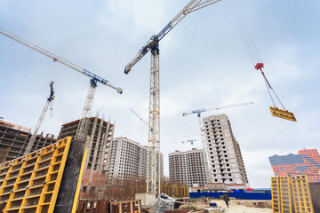 Work of the crane on the construction site, against the background of the cloudy sky. Daylight.