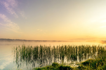 Fototapeta na wymiar Sunrise by lake at foggy morning