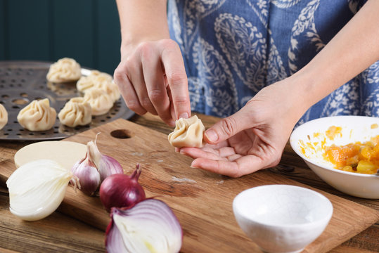 Cooking vegetarian meal. Woman hands making traditional Asian steamed dumplings with pumpkin, onion and ginger