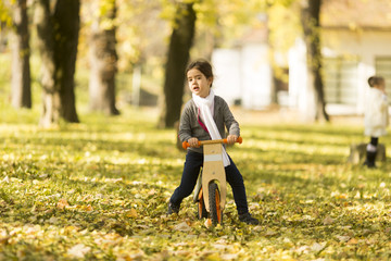 Little girl riding bicycle in autumn park