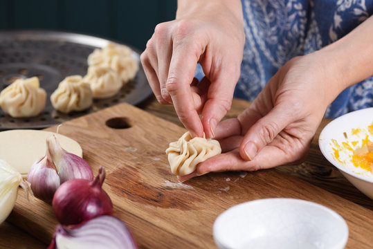 Woman in kitchen making vegetarian steam dumplings momo with pumpkin, garlic and onion