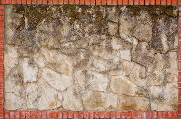 Fototapeta premium Wall of natural light stone in a red brick frame.
