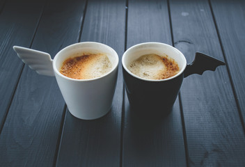 Two cups of coffee. White and black.