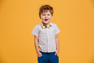 Funny little boy child standing isolated over yellow