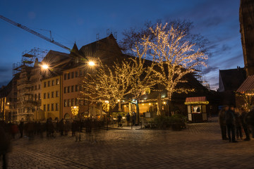 Stands at the Christmas market in Nuremberg during blue hour with lights in the trees