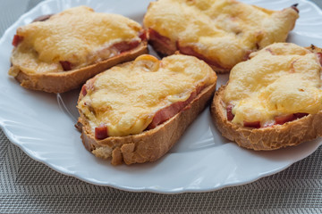 close-up of baked hot sandwiches with cheese and sausage on white plate